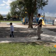 A first grade child uses his cane to guide Steve through his playground at school.